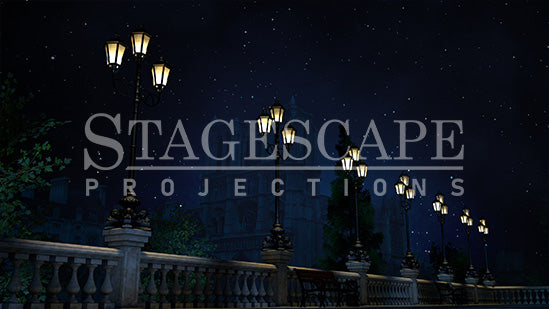 Paris Riverside Promenade static scenic projection backdrop for & Juliet — oil lamps along the Seine with Notre Dame in the distance. Five lighting states from dusk to night. StageScape Projections.