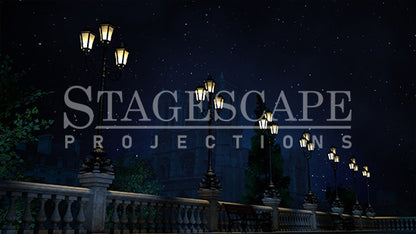 Paris Riverside Promenade static scenic projection backdrop for & Juliet — oil lamps along the Seine with Notre Dame in the distance. Five lighting states from dusk to night. StageScape Projections.